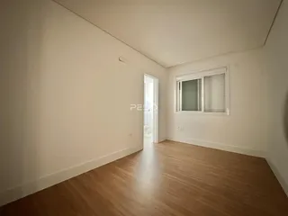 Vista interna de um cômodo com piso de madeira e paredes brancas.