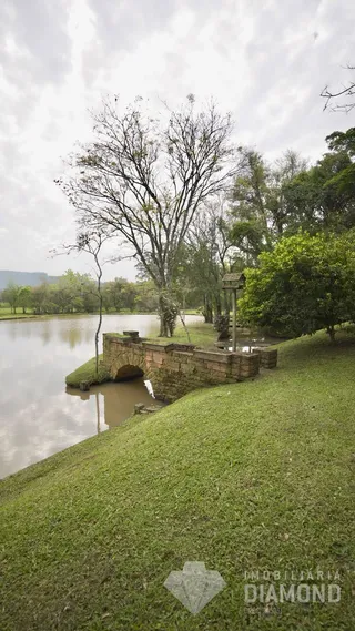 Vista de um corpo d'água com uma ponte de pedra e gramado na paisagem.