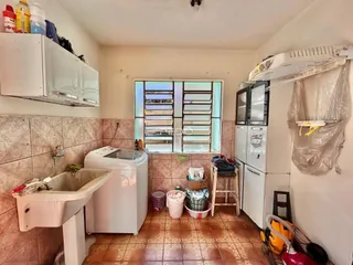 Interior de uma área de serviço com azulejos e pia.