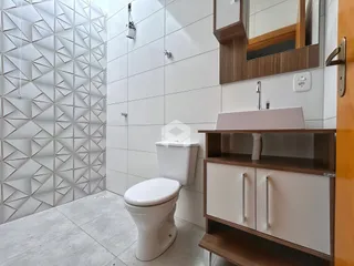 Banheiro moderno com revestimento de azulejos brancos e bancada de madeira.