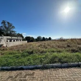 Vista externa de um campo seco e gramado com céu azul claro.