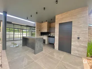 Ambiente moderno com piso de pedra e grandes portas de vidro.