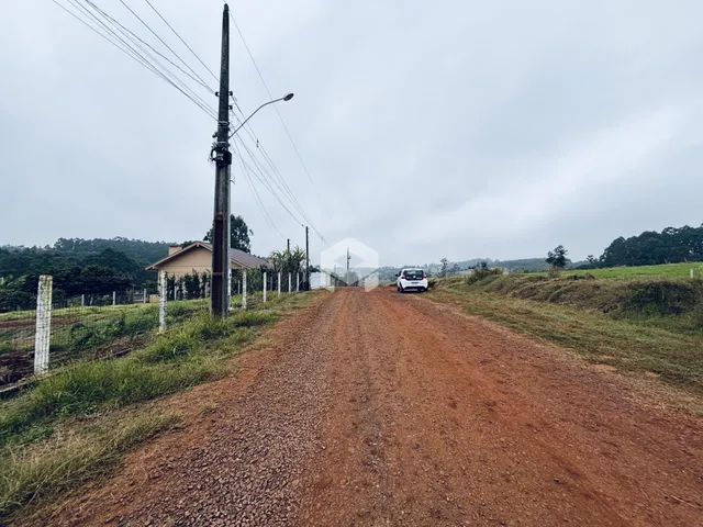 Uma estrada de terra leva a uma propriedade rural na paisagem.