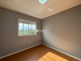 A sala apresenta paredes cinzas e piso de madeira com uma janela.