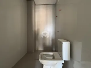 Vista de um corredor com um vaso sanitário em um imóvel.