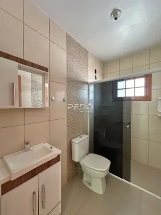 Foto de um banheiro interno com azulejos brancos e louças sanitárias.
