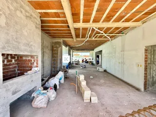 Foto de um espaço interno em fase de construção com vigas de madeira expostas.