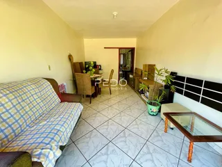 Imagem de uma sala de estar com sofá e área de jantar em um imóvel no Brasil.
