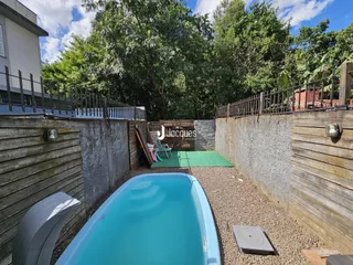 Foto de uma piscina externa em uma propriedade com cerca de madeira e muro de concreto.