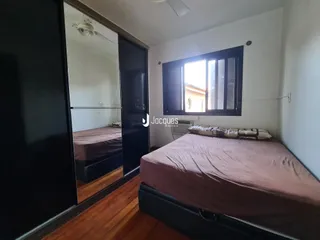 Quarto com cama e piso de madeira no interior da residência.