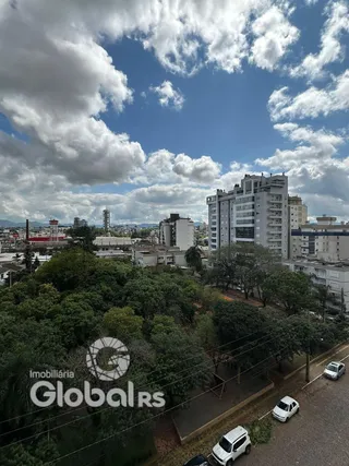 Vista aérea de uma área residencial com vegetação densa e edifícios ao fundo.