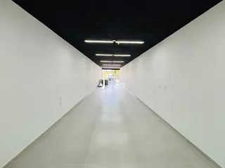 Corredor longo com paredes brancas e teto preto.