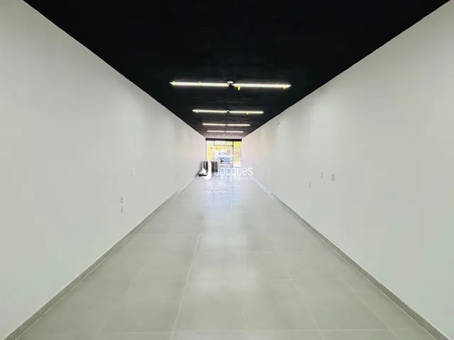 Corredor longo com paredes brancas e teto preto.