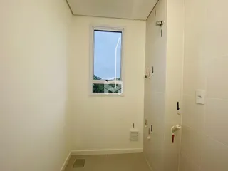 Corredor interno com parede revestida e janela em um imóvel no Brasil.