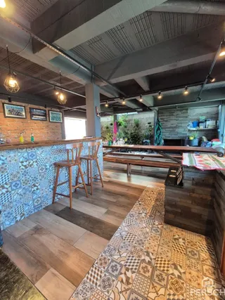 Ambiente interno com piso de madeira e parede de azulejos decorativos.