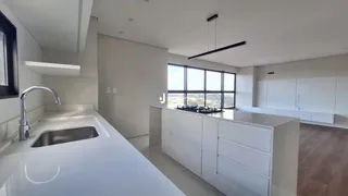 Vista da cozinha moderna com armários brancos e janela grande.