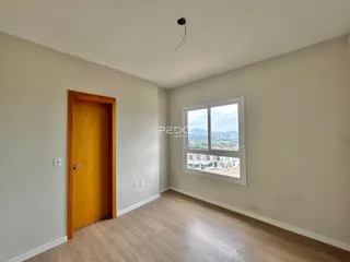 Ambiente interno de uma sala com piso de madeira e janela com vista para a paisagem.