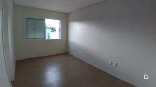 Ambiente interno com piso de madeira clara e parede branca.