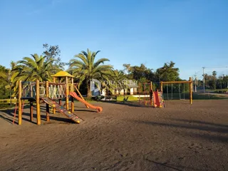 Área externa com playground de madeira em um terreno.