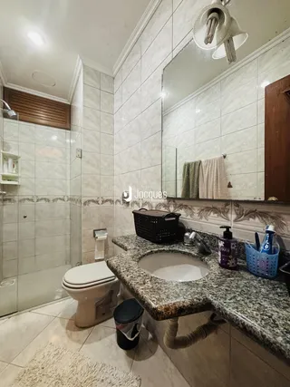Banheiro com revestimento de azulejo e bancada de granito.