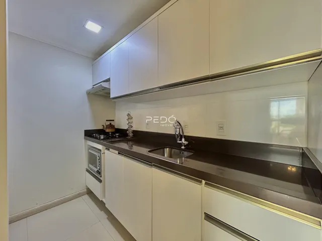 Vista da cozinha moderna com armários brancos e bancadas escuras.