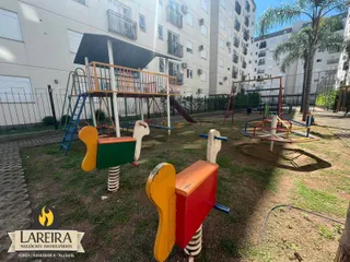 Foto da área externa com equipamentos de playground e gramado.
