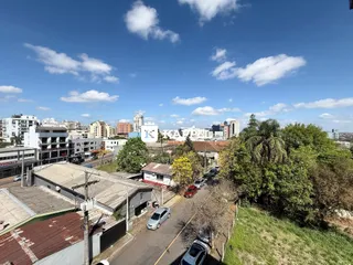 Vista aérea mostrando uma rua residencial com vegetação e edifícios na área.