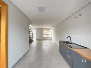 Corredor interno de uma residência com paredes brancas e piso claro.