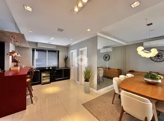 Sala de estar com cozinha integrada e piso claro.