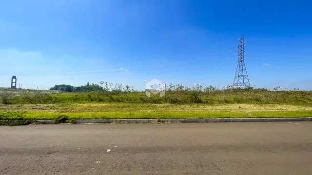 Paisagem de campo com estrada e vegetação no horizonte.