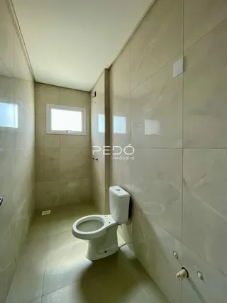 Corredor interno com revestimento de cerâmica e vaso sanitário branco.