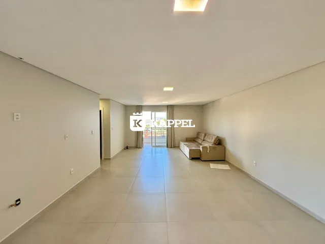 Uma sala de estar longa e clara com piso de cerâmica e sofá no final.