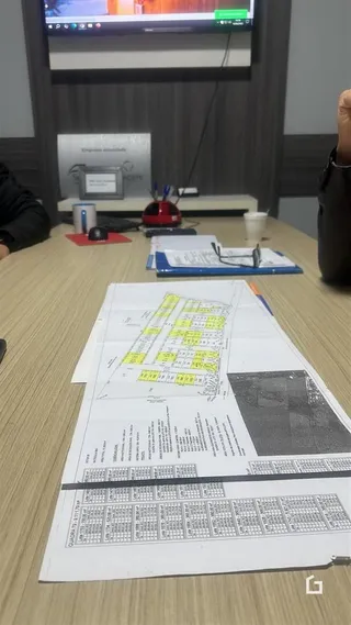 Documentos de planta e detalhes de propriedade estão dispostos sobre uma mesa.