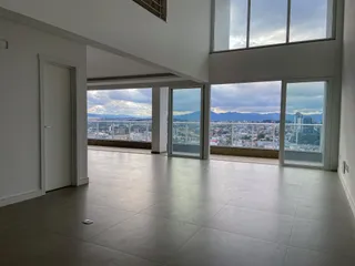 Sala ampla com grandes janelas oferecendo uma vista panorâmica da paisagem urbana.