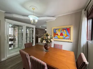 Sala de jantar com mesa de madeira e cadeiras em um imóvel no Brasil.