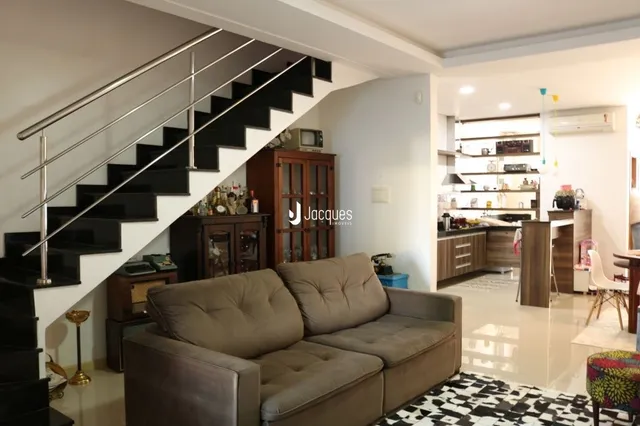 Interior de uma sala com escadaria e sofá.