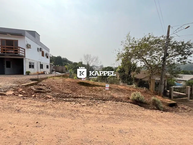 Fachada de uma residência branca em Lajeado, Brasil, com terreno seco em primeiro plano.