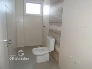 Banheiro com revestimento cerâmico e paredes brancas.