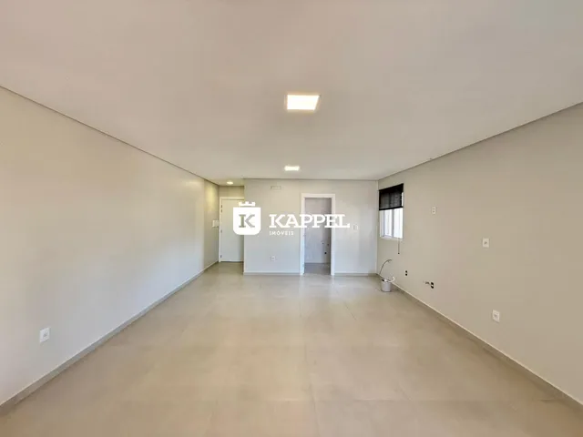 Hall de entrada amplo e claro com piso de cerâmica e paredes brancas.