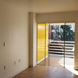 Vista de uma porta de vidro que dá acesso a uma área externa com degraus.