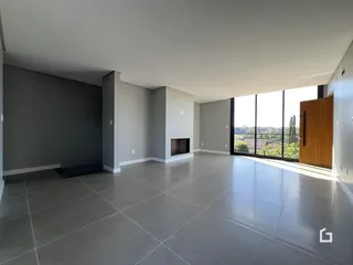 Ambiente interno de uma sala ampla com piso de cerâmica e grande janela.