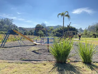 Vista externa de um jardim com playground e vegetação exuberante.