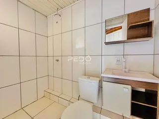 Foto do interior de um banheiro com revestimento de cerâmica branca.