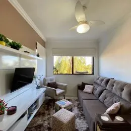 Foto interna de uma sala de estar com prateleiras brancas e teto com ventilador.