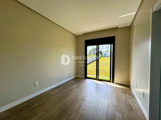 Ambiente interno com piso de madeira clara e porta de vidro que dá para o exterior.