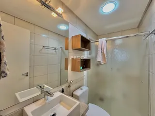 Foto de um banheiro com revestimento cerâmico e box de vidro.