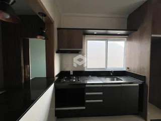 Vista da cozinha moderna com armários escuros e bancada preta.