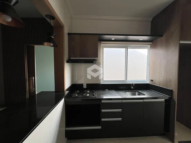 Vista da cozinha moderna com armários escuros e bancada preta.