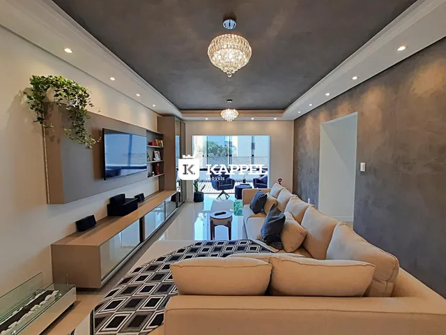 Sala de estar moderna com sofá grande e televisão montada na parede.