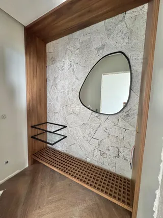 Parede decorativa com revestimento de pedra e espelho em um ambiente interno.
